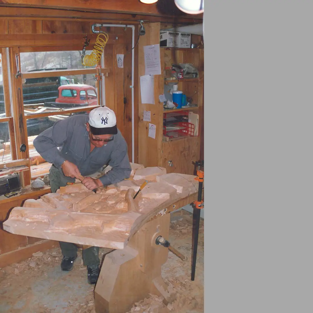 A man with a cap is carving a sculpture